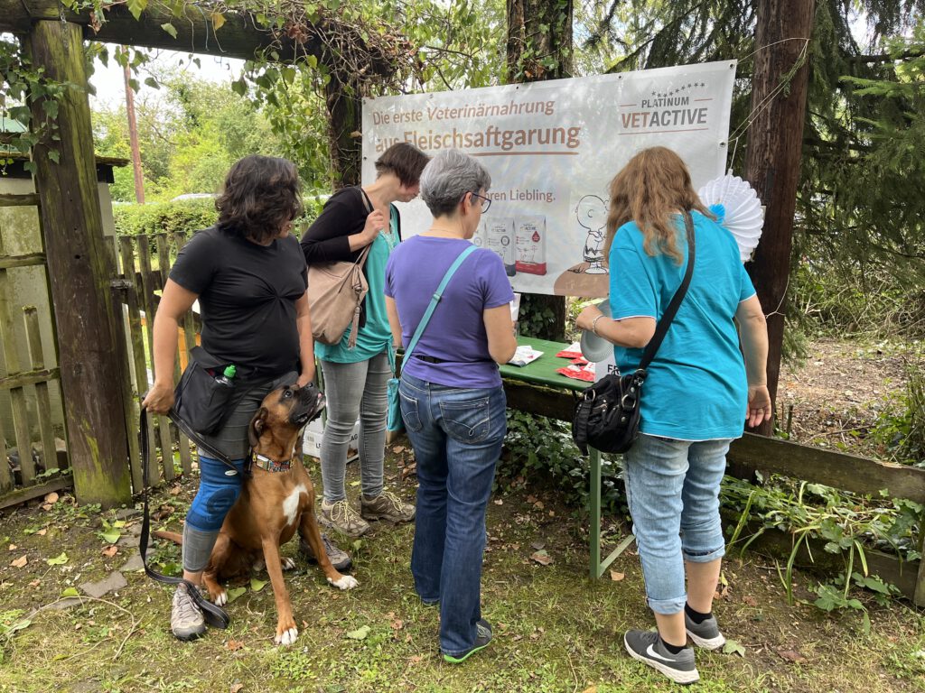 mehrere Frauen betrachten einen Stand mit Hundefutter beim Sommerfest 2024